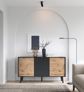 Komoda loftowa ryflowana Willow K154 to połączenie nowoczesnej formy z industrialnym charakterem. Jej czarny korpus kontrastuje z dekoracyjnymi, ryflowanymi frontami w naturalnym odcieniu drewna, tworząc wyrazisty i stylowy akcent we wnętrzu. Mebel wyposażono w trzy fronty otwierane systemem push to open, co podkreśla jego minimalistyczny wygląd i zapewnia wygodę użytkowania. Osadzona na smukłych, czarnych nóżkach, komoda prezentuje się lekko i elegancko. Idealna do salonu, jadalni lub przedpokoju w stylu loft, modern czy scandi.